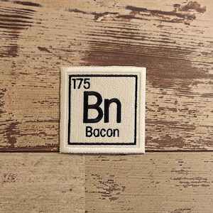 May include: A white square patch with black stitching around the edges. The patch has a white background with black text that reads "175 Bn Bacon".