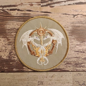 May include: A beige circular patch with an embroidered design of two white dragons facing each other around a golden sun with a golden star above it.