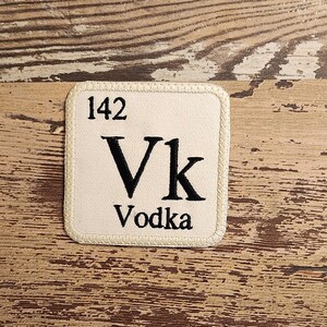 May include: A white square patch with a black stitched border and the text "142 Vk Vodka" inside.