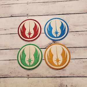 May include: Four embroidered patches featuring the Star Wars Rebel Alliance symbol. The patches are in red, blue, green, and gold.