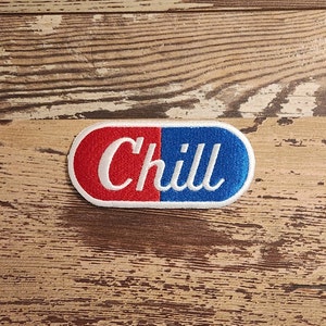 May include: A red and blue pill-shaped patch with white embroidered text that reads "Chill".