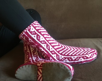 May include: Red and white knitted slippers with a suede sole. The slippers have a geometric pattern.