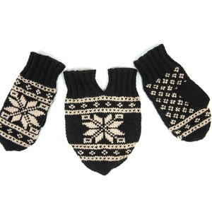May include: A set of three black and beige knitted winter accessories: two mittens and a mitten-scarf combination. Each piece features a snowflake or geometric pattern in beige against a black background. The items are arranged on a white background.