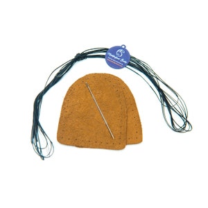May include: Two brown leather heel patches with holes for stitching, a needle, and a spool of black thread. The spool has a label that reads "Hobbledehoy Socks".