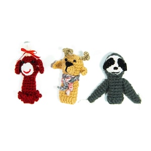 May include: Three crocheted finger puppets: a red dog, a brown reindeer with a white and gray scarf, and a gray sloth.