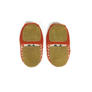 May include: A pair of red knitted slippers with brown suede soles. The slippers have a white and green geometric pattern.
