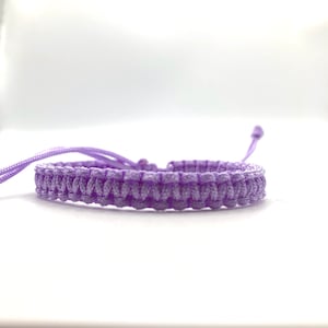 May include: A purple braided bracelet with adjustable closure.