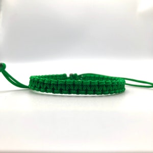 May include: A green braided bracelet with adjustable closure.