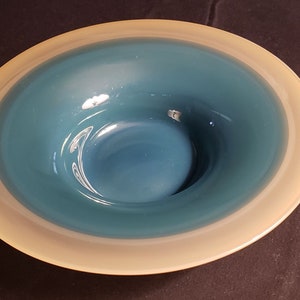 Könnte beinhalten: Eine hellblaue Glasschüssel mit weißem Rand. Die Schüssel hat eine glatte, glänzende Oberfläche.