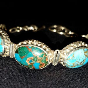 Pode incluir: Uma pulseira de prata com cinco pedras ovais de turquesa engastadas em prata. As pedras têm um padrão de mármore azul e verde.