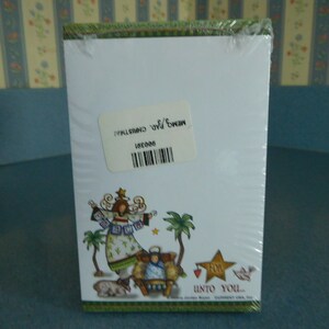 May include: A Christmas notepad with a green, white, and red design. The notepad features an illustration of an angel with a star and the text "Unto You..."
