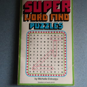 May include: A book cover with the title "SUPER WORD FIND PUZZLES" in red, yellow, and blue letters. The cover features a word search puzzle with the words "GENJOYABLE", "GMDNIM", "DROW", "BIROMOS", "TOU", "TTRICKY", "AKH", "LNKRKS", "LEFS", "PUZZLE", "SRDR", "NFAWA", "EDGDE", "EIES", "AKHZOS", "VNYRY", "TNUWA", "LDC", "QBRAINE", "OHIDDEN", "LLT", "SRTZCLUEIN". The book is by Michelle Eldredge and the solution is on the back cover.