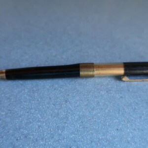 May include: A black and silver mechanical pencil with a retractable tip. The pencil has a gold band near the tip.