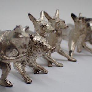 以下が含まれることがあります： 銀色の動物の置物のコレクション。キツネやクマなど、金属製のようです。動物たちは様々なポーズをとっており、立っているものもいれば、しゃがんでいるものもいます。