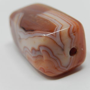 Peut inclure: Une perle en agate brune et blanche avec un trou percé. La perle a une forme naturelle irrégulière et est polie.