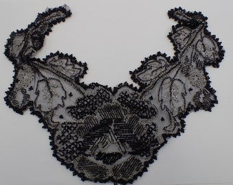 May include: Black and silver lace trim with a floral design. The lace is delicate and intricate, with a scalloped edge.
