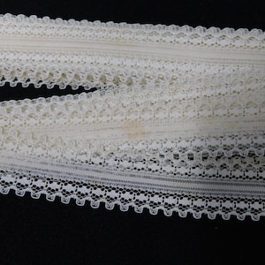 Peut inclure: Garniture en dentelle blanche avec un motif délicat. La garniture est faite d'un matériau doux et léger et a un bord festonné.
