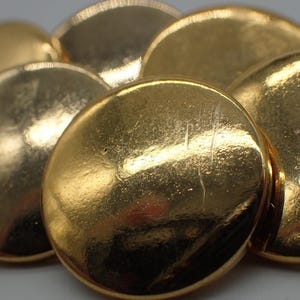 Peut inclure: Un groupe de six boutons ronds de couleur dorée. Les boutons sont lisses et brillants.