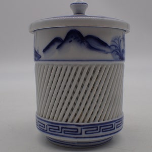 以下が含まれることがあります： 青と白の山を描いた白い陶器の壺。蓋と中央に格子模様がある。