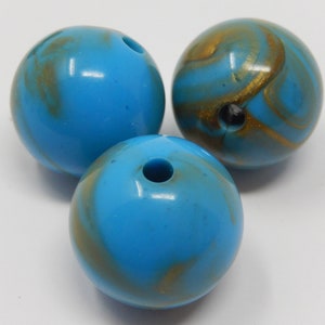 May include: Three round blue and gold marbled beads. The beads have a hole in the centre for stringing.