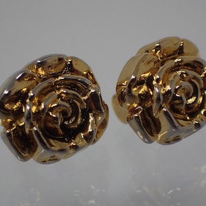 以下が含まれることがあります： バラの形をしたゴールドトーンのスタッドピアスのペア。バラは渦巻き模様で詳細に描かれており、ツートーン仕上げになっています。