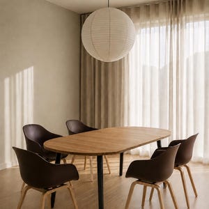 May include: A modern dining room set featuring a light brown oval table with black legs, surrounded by six brown chairs with wooden legs. A large paper lantern hangs from the ceiling, and sheer curtains are in the background.