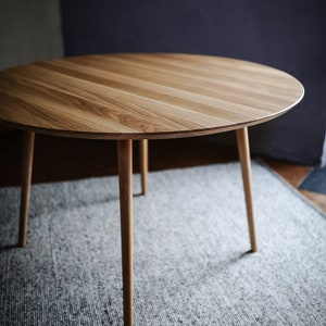 Round dining table made from reclaimed oak wood with a shark edge in natural on danish tapered legs. Fully customisable to your needs