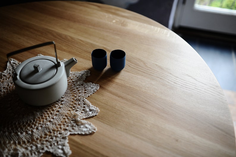 Round dining table made from reclaimed oak wood with a shark edge in natural on danish tapered legs. Fully customisable to your needs