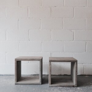 May include: Two wooden cube-shaped end tables with open shelves. The tables are made of reclaimed wood and have a natural finish.