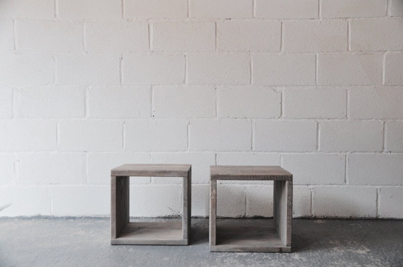 May include: Two wooden cube-shaped end tables with open shelves. The tables are made of reclaimed wood and have a natural finish.