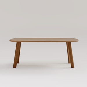 May include: A light brown wooden table with a rectangular top and four angled legs. The table has rounded corners and a smooth finish. The legs are slightly tapered, giving the table a modern look. The table is approximately 60 inches long.