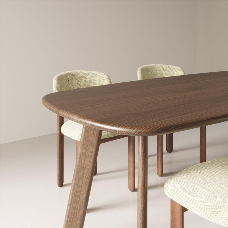 May include: A dark brown wooden dining table with rounded corners and angled legs. Two chairs with light green patterned upholstery are visible, along with a portion of a third chair. The table and chairs have a modern, minimalist design.