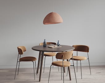 May include: A modern dining set featuring a round, dark wood table surrounded by four chairs with brown upholstered seats and black metal legs. A matching pendant light hangs above. Two blue glass bottles and a wooden tray are on the table.