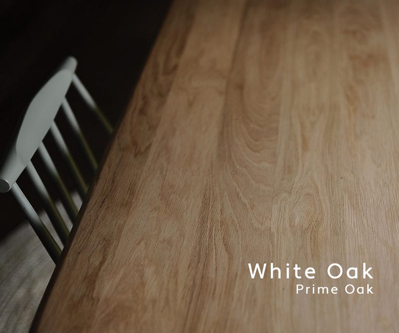 May include: A close-up of a light-colored wooden table with visible wood grain. The text "White Oak Prime Oak" is displayed on the table. A white chair is partially visible in the upper left corner.