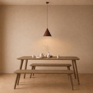 May include: A dining room with a wooden table and benches. A brown, cone-shaped pendant light hangs above. The table is set with a white tea set and cups. The room has a neutral colour scheme, with a warm, inviting atmosphere.