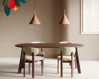 Può includere: Un tavolo da pranzo ovale in legno scuro con quattro sedie dotate di sedute e schienali imbottiti di colore chiaro. Due lampade a sospensione coniche sono appese sopra il tavolo. Nell'angolo è presente una grafica decorativa con una pallina rossa e foglie verdi.