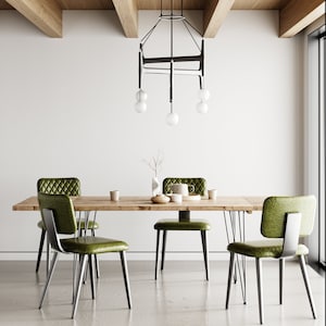 Può includere: Un tavolo da pranzo in legno con quattro sedie imbottite verdi e un lampadario in metallo nero con cinque lampadine bianche a globo appese sopra.