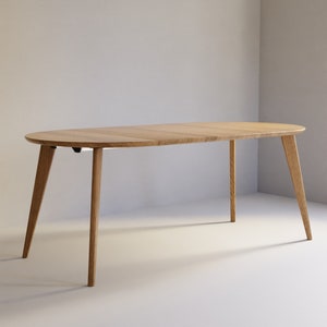 May include: An oval dining table crafted from light-toned wood with a smooth, flat surface and four tapered legs that angle outward. The table features a visible seam across the center, indicating a modular or extendable design construction.