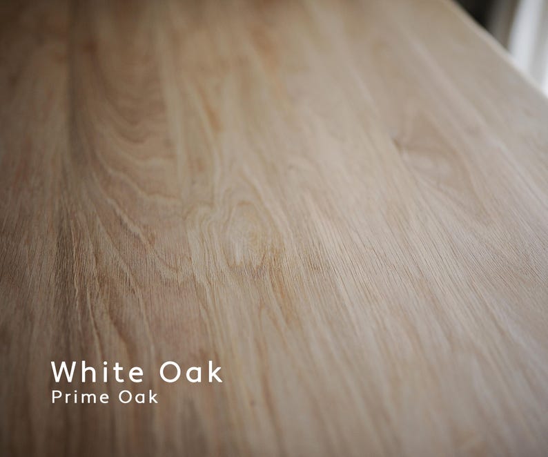 May include: Close-up of a light-colored, textured wood surface. The grain of the wood is visible, with a natural pattern of lines and swirls. The text "White Oak Prime Oak" is displayed in white.
