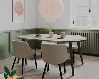 May include: An oval wooden dining table with four light beige upholstered chairs featuring dark wooden legs. A large white spherical pendant light hangs above the table, which is set with a small vase, a bowl, and a pitcher in a room with green walls.
