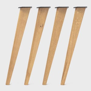 Puede incluir: Cuatro patas de mueble c&oacute;nicas hechas de madera de color marr&oacute;n claro con patrones de veta visibles. Cada pata cuenta con una placa de montaje de metal oscuro plana en la parte superior, inclinada para soportar muebles con un perfil esbelto.
