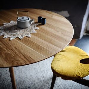 Round dining table made from reclaimed oak wood with a shark edge in natural on danish tapered legs. Fully customisable to your needs