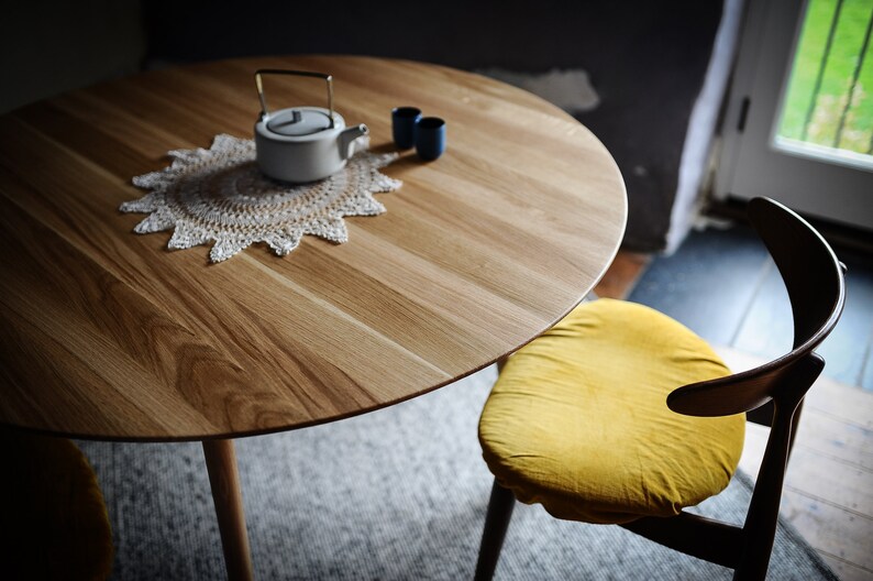 Round dining table made from reclaimed oak wood with a shark edge in natural on danish tapered legs. Fully customisable to your needs