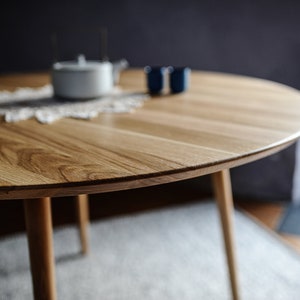 Round dining table made from reclaimed oak wood with a shark edge in natural on danish tapered legs. Fully customisable to your needs