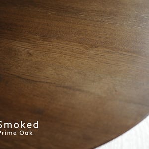 Puede incluir: Primer plano de una superficie de madera de color marr&oacute;n oscuro con vetas visibles. El texto "Smoked Prime Oak" se muestra en blanco en la parte inferior de la imagen.