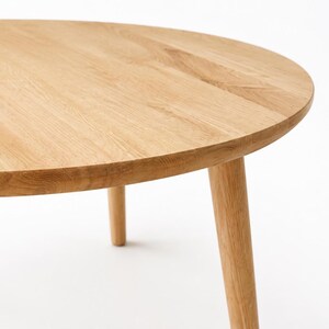 Puede incluir: Una mesa de centro redonda de madera clara con tres patas redondeadas. La tapa es de madera maciza y tiene un patr&oacute;n de vetas naturales. La mesa tiene aproximadamente 76 cm de di&aacute;metro.