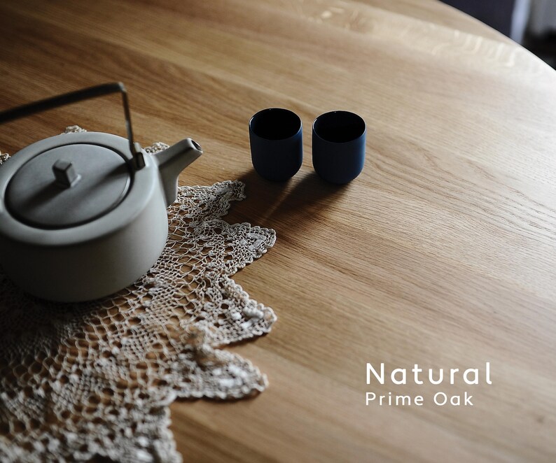 Puede incluir: Una tetera gris claro con asa y boquilla negras se encuentra sobre un tapete de encaje color crema. Dos tazas peque&ntilde;as de color azul oscuro est&aacute;n junto a la tetera. El texto "Natural Prime Oak" est&aacute; en la esquina inferior derecha.