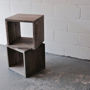 May include: Two wooden cube shelves stacked on top of each other. The shelves are made of reclaimed wood and have a rustic finish. The shelves are empty.