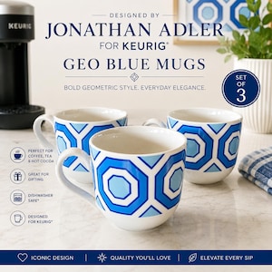 May include: A set of three white ceramic mugs featuring a bold geometric pattern in shades of blue. The mugs are labeled as Geo Blue Mugs designed by Jonathan Adler for Keurig. Each mug has a curved handle and a wide opening for hot beverages.