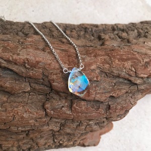 May include: A silver chain necklace with a iridescent, faceted gemstone pendant.